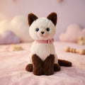 Cremefarbene und braune sitzende Plüschkatze mit rosa Halsband
